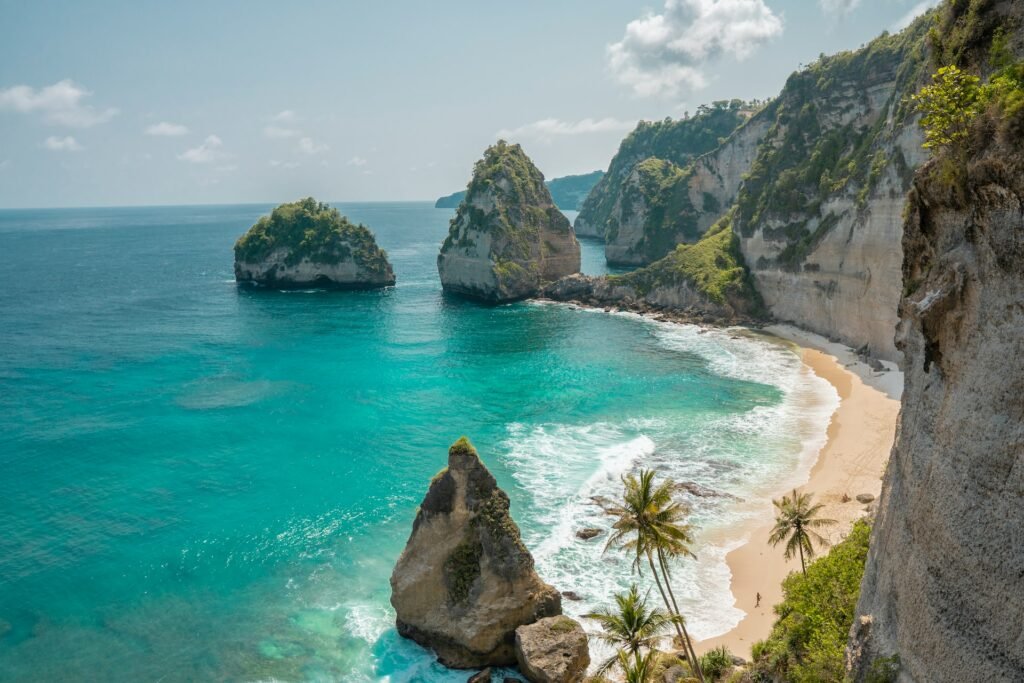 vista da Nusa Penida, uma praia de águas esverdeadas cristalinas, com poucas ondas e areia amarelinha com pedras e paredes, para ilustrar o post chip celular Bali