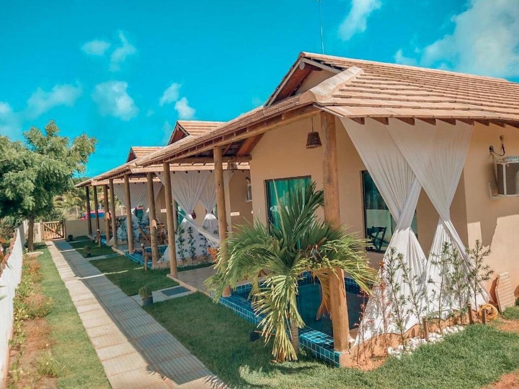 Vista de fora do Bellíssimo Villaggio. Do lado direito a área de fora das acomodações com uma mini piscina em cada varanda. Do lado esquerdo o corredor do chalé com um jardim e um caminho de piso.