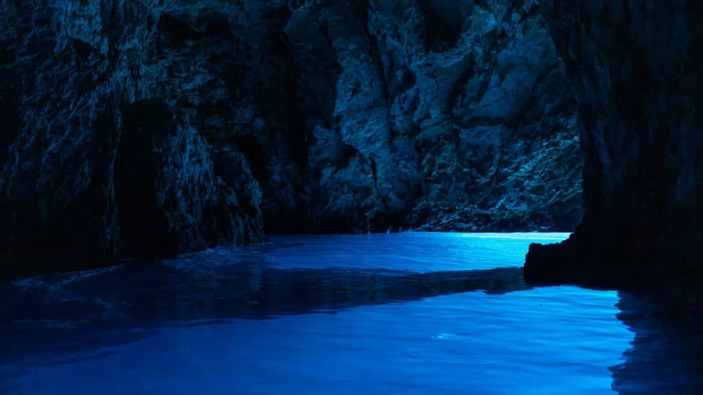 Imagem da parte interna da Gruta Azul, na Croácia, que reluz uma luz fluorescente na água azul. 