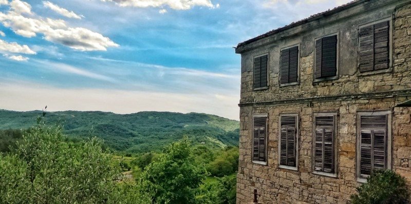 vista panorâmica da pequena cidade de Hum, na Ístria. No cando direito há uma construção de pedra com as janelas fechadas