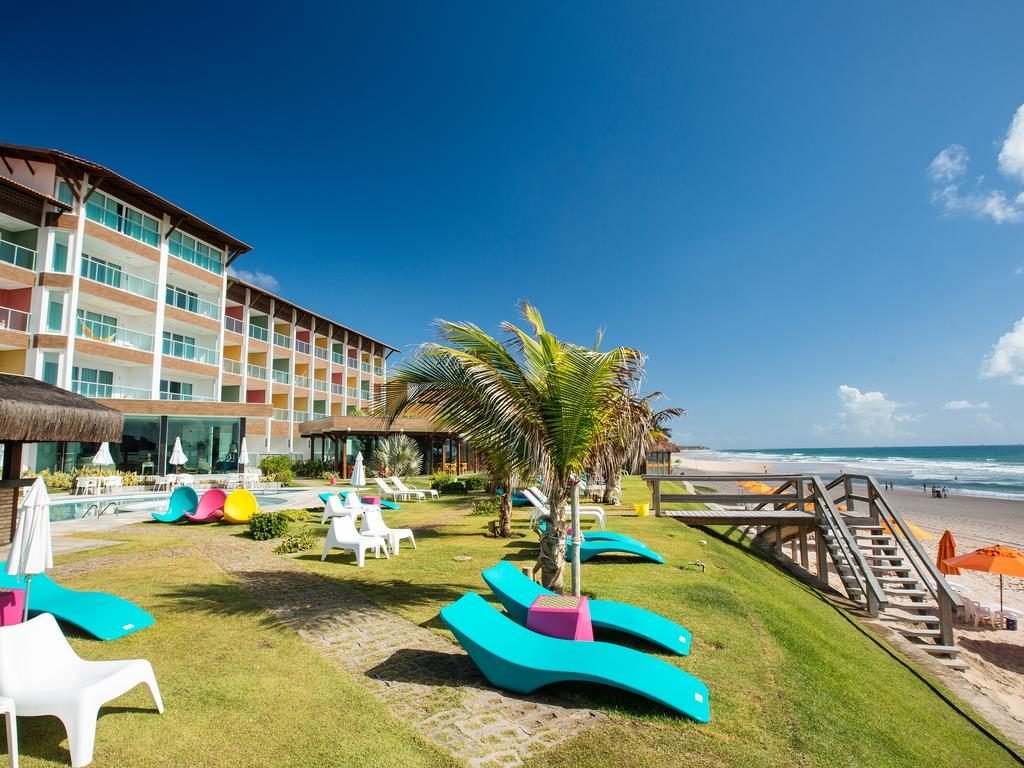 Área externa do Kembali Hotel. A praia do lado direito, no meio cadeiras de tomar sol, e no lado esquerdo o hotel.