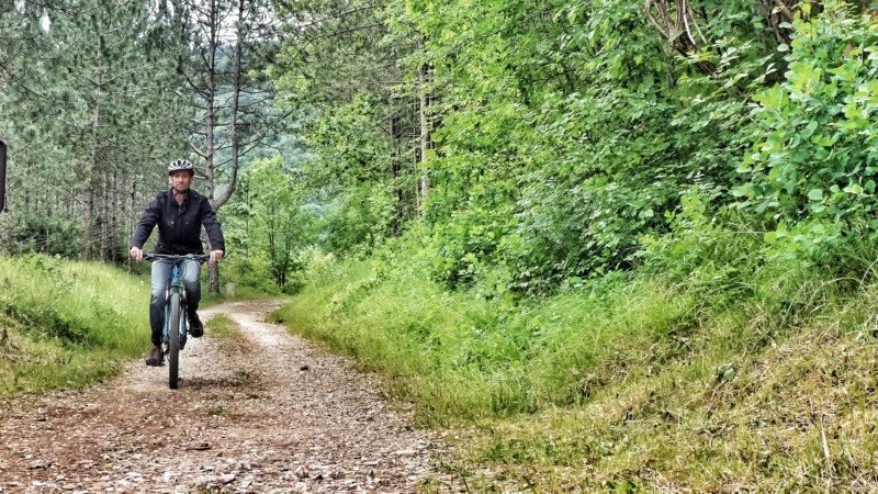 homem andando de bike numa estrada de cascalho em meio a floresta de groznjan, na Ístria