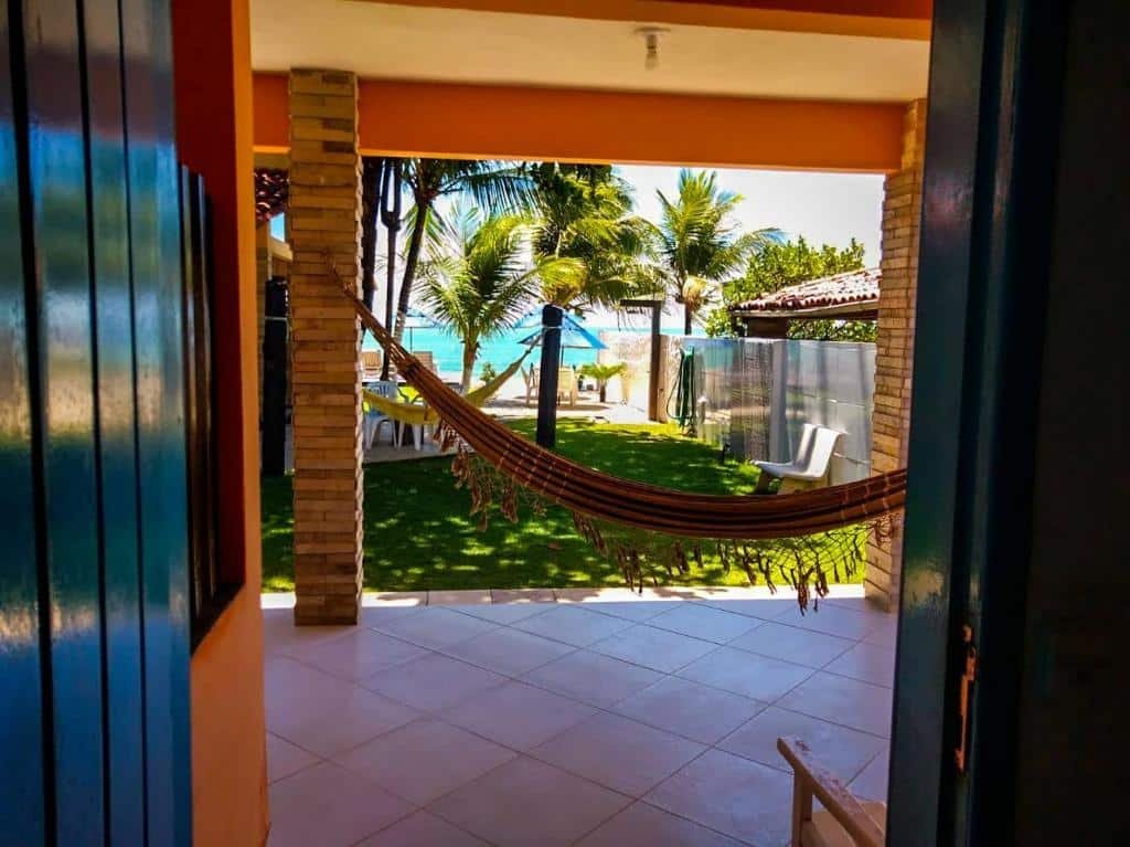 Vista da porta do quarto da Pousada Santo Aleixo. Uma rede, um jardim, e no fundo a praia.