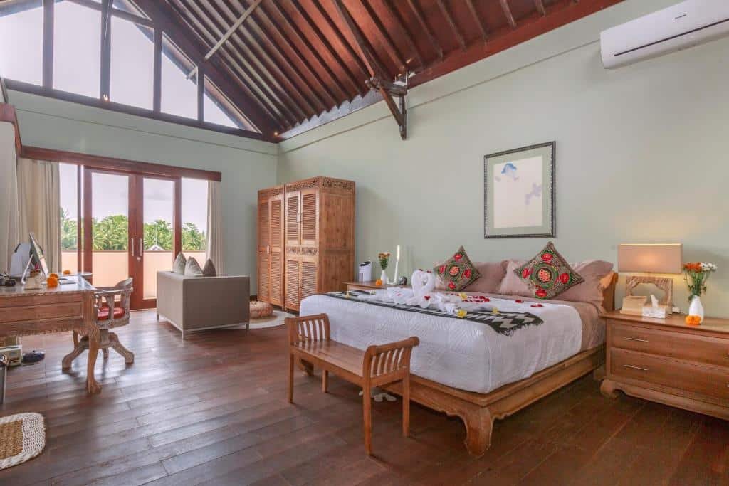 Quarto espaçoso  do Solo Villas & Retreat com móveis de madeira, uma cama grande, almofadas decorativas, uma pequena área de estar e luz natural proveniente de grandes janelas.