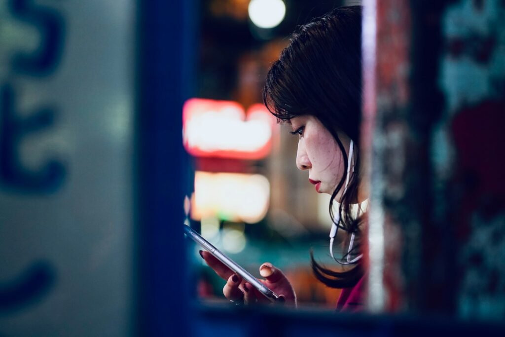 Uma mulher branca com traços orientais sentada usando o celular